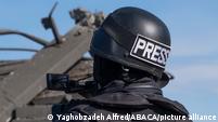 Person wearing a helmet saying "Press" from behind