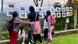 Participants at a community event look at photos hung on a clothesline