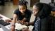 Two women collaborate at a computer.