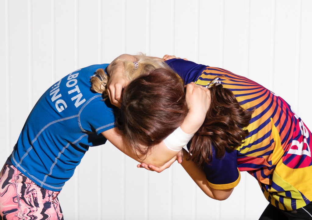 Two figures in brightly coloured sports wear, grappling. Spiral Holds #03, Phoebe Davies, 2020