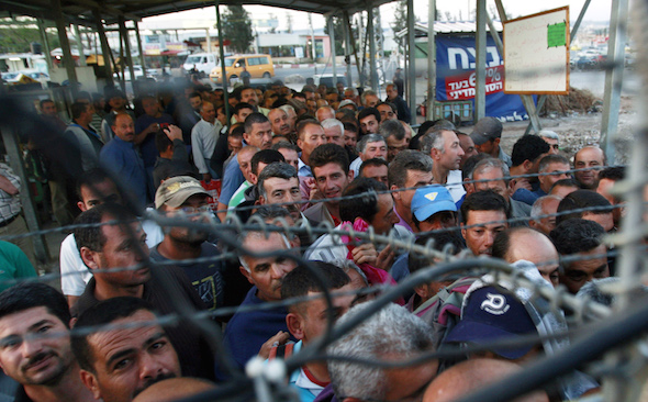 Palestinian workers wait to cross at the Israeli checkpoint in Jalameh, south of the West Bank city of Jenin, on their way to work in Israel. (Mohammed Ballas / AP)