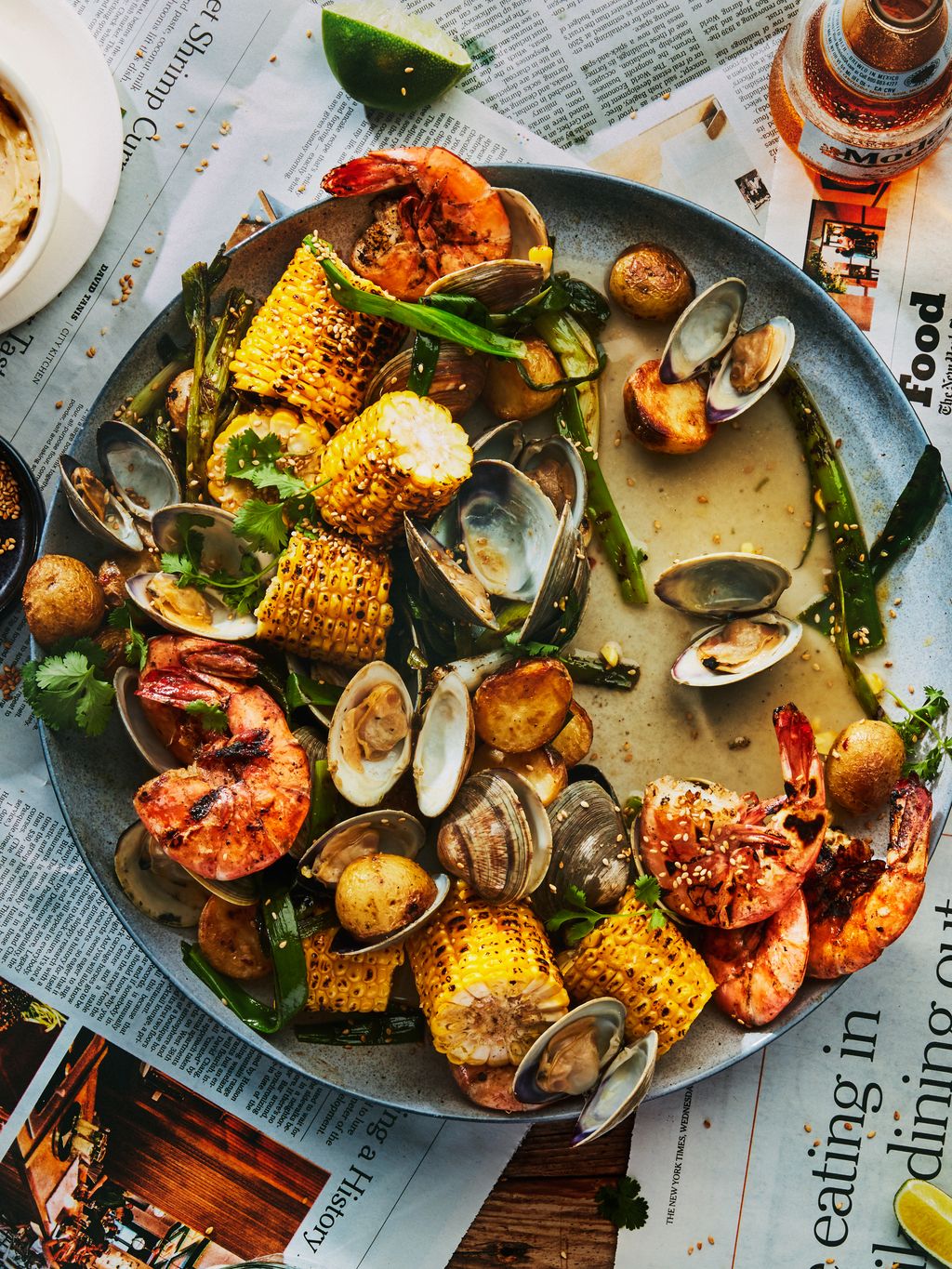 Clams shrimp and corn in a big bowl on a newspapercovered table.