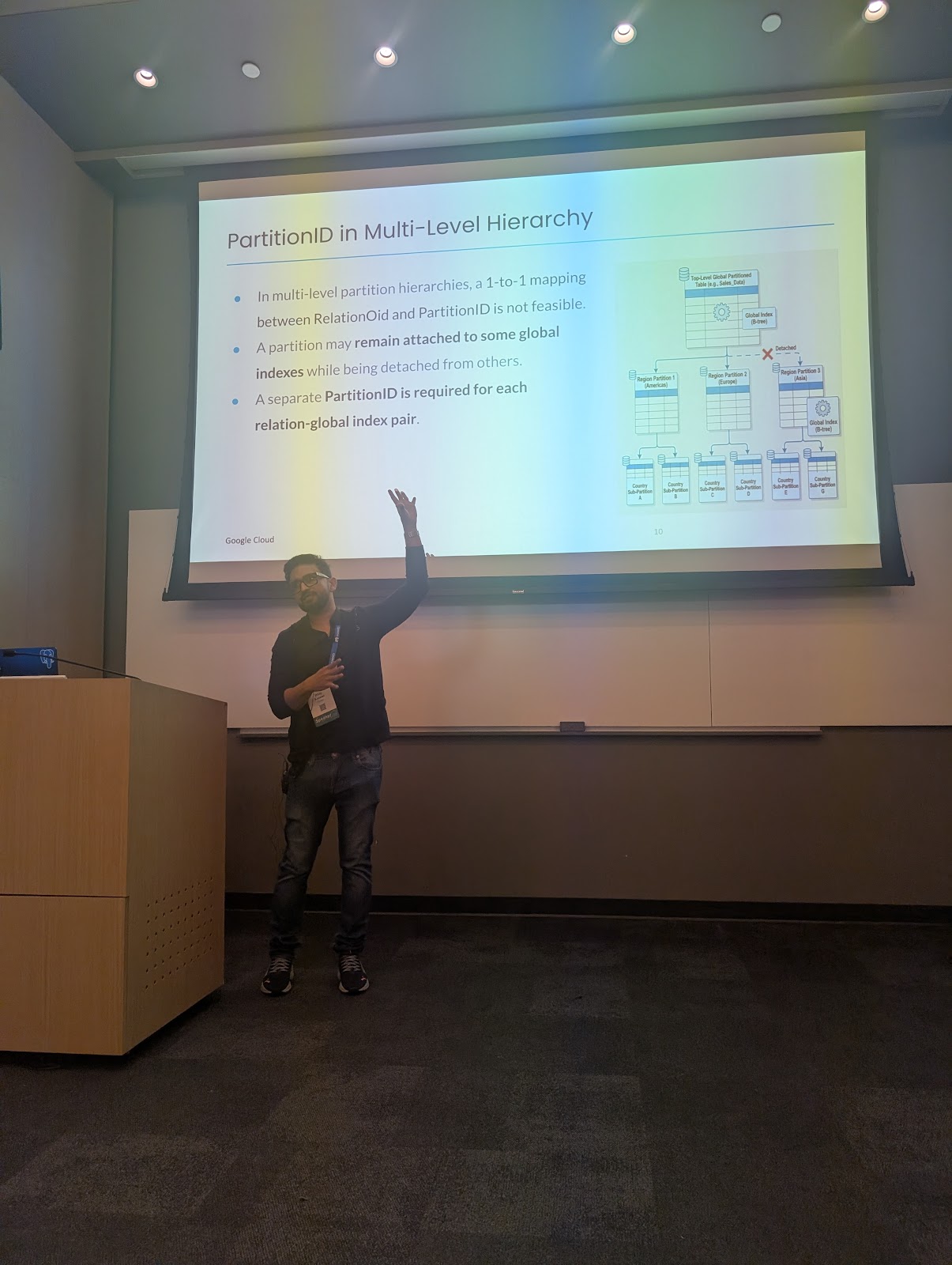 ilip Kumar, a PostgreSQL contributor from Google Cloud, presenting 'Experimenting with a Global Index in PostgreSQL' at pgconf.dev 2026 in Vancouver. He is speaking at a podium next to a presentation slide detailing the Global Index storage architecture and PartitionIdentifier management.