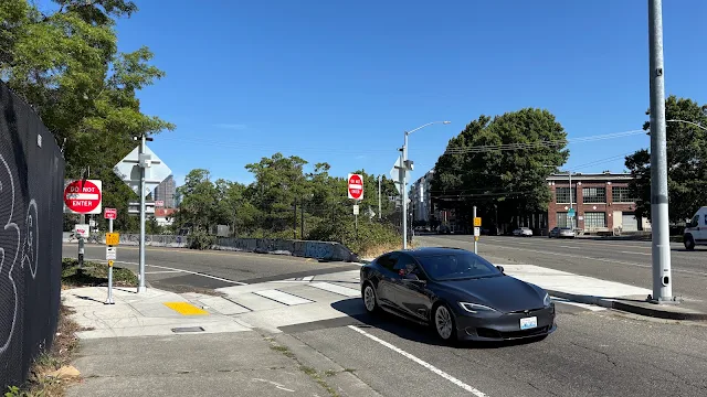 A raised crosswalk and rectangular crossing beacons on a freeway off-ramp, with a car crossing over the crosswalk.
