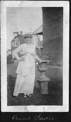 a kindly looking older woman standing in her garden