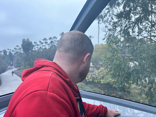 Leo riding the Disneyland Monorail Photo of Leo, from behind and wearing a red hoodie, riding the Monorail at Disneyland