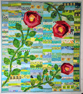 Blue and green Chinese Coins form a backdrop for three large red roses on this quilt