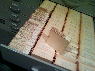 a drawer with boxes upon boxes 4 inch square and an inch thick containing reels of microfilm