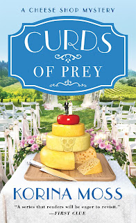 Curds of Prey by Korina Moss Book cover showing a stack of round cheeses set up at an outdoor wedding