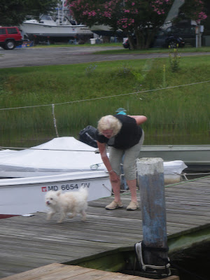 barley, the little white dog owned by the one legged lady getting patted by a woman on the dock