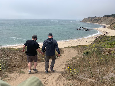 Leo and his dad, seen from behind, walking down a trail to a cove.