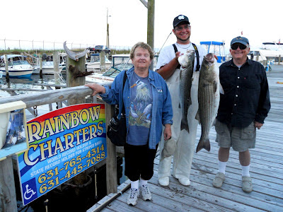 my mom and dad, boat mate holding up to very large striped bass about 25 pounds in size