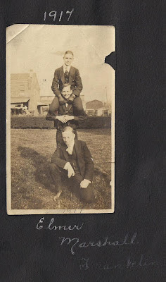 3 skinny young men stacked up on each other's shoulders