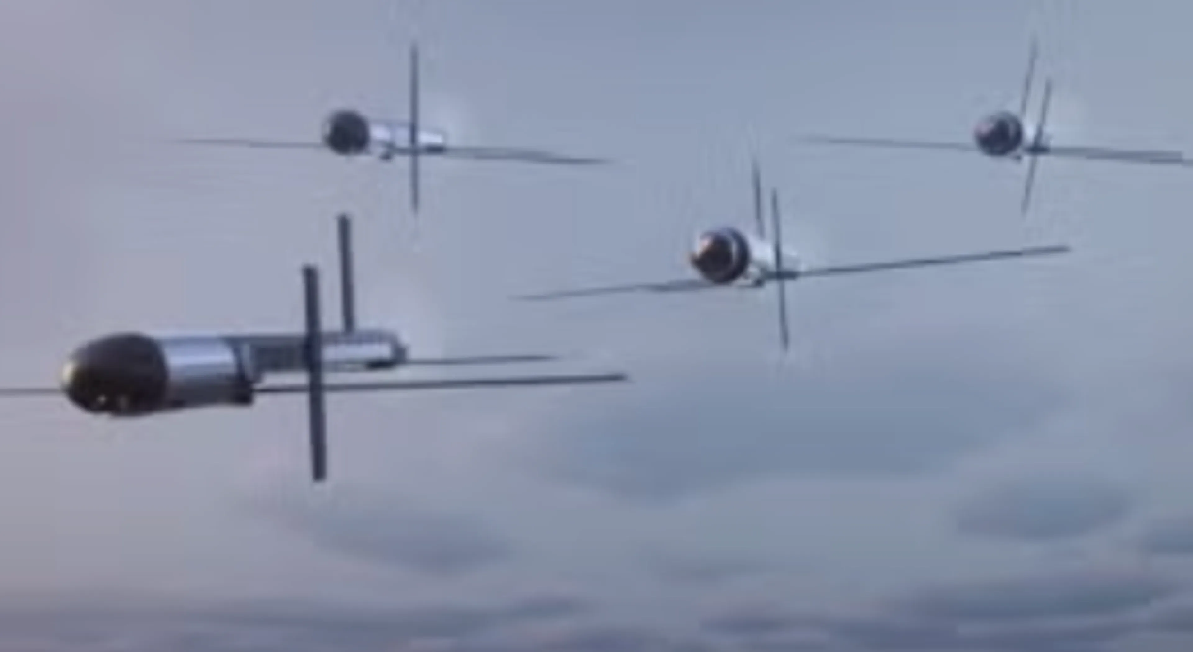 Four small unmanned aircraft with slender wings flying in formation against a cloudy sky.