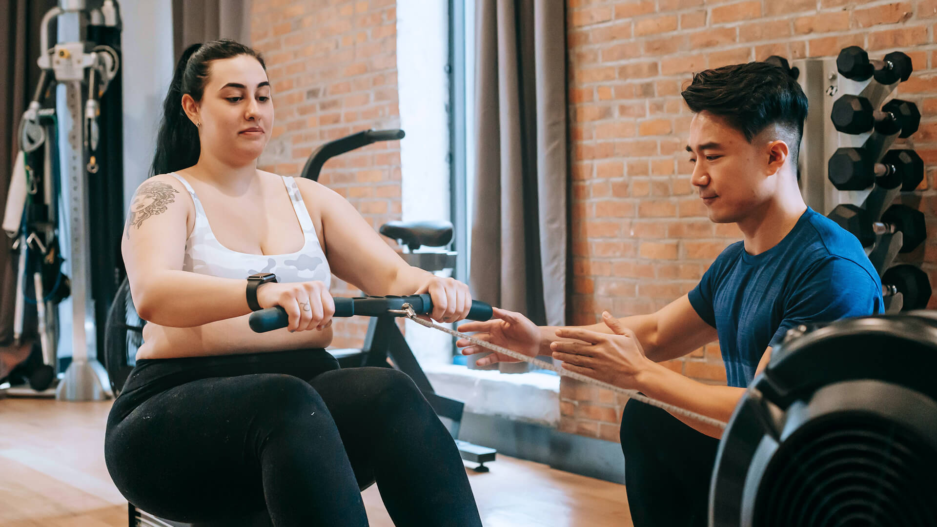 Woman rowing for weight loss with coach