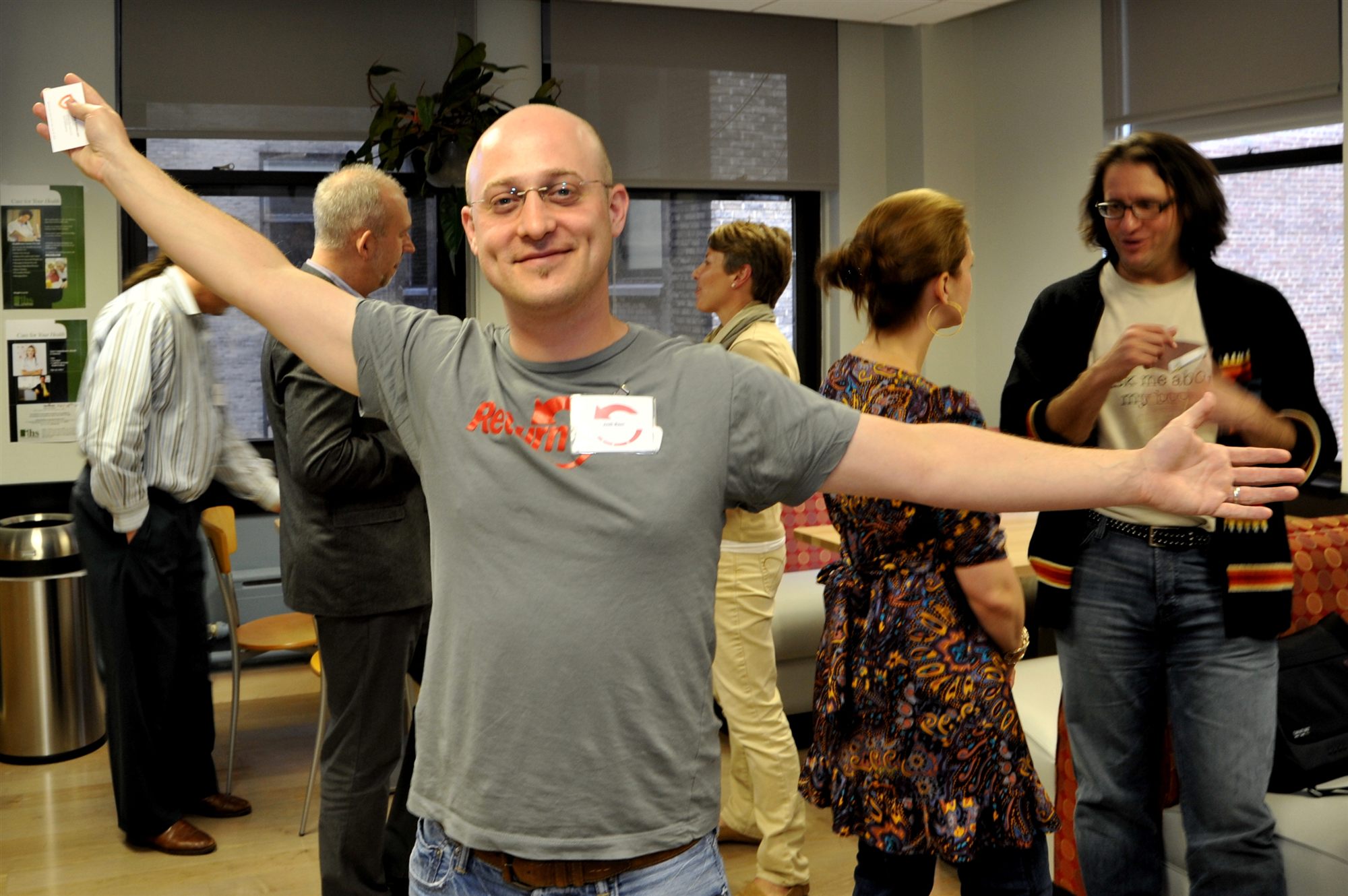 Josh Baer at a Return Path event, arms thrown wide and grinning, wearing a Return Path t-shirt