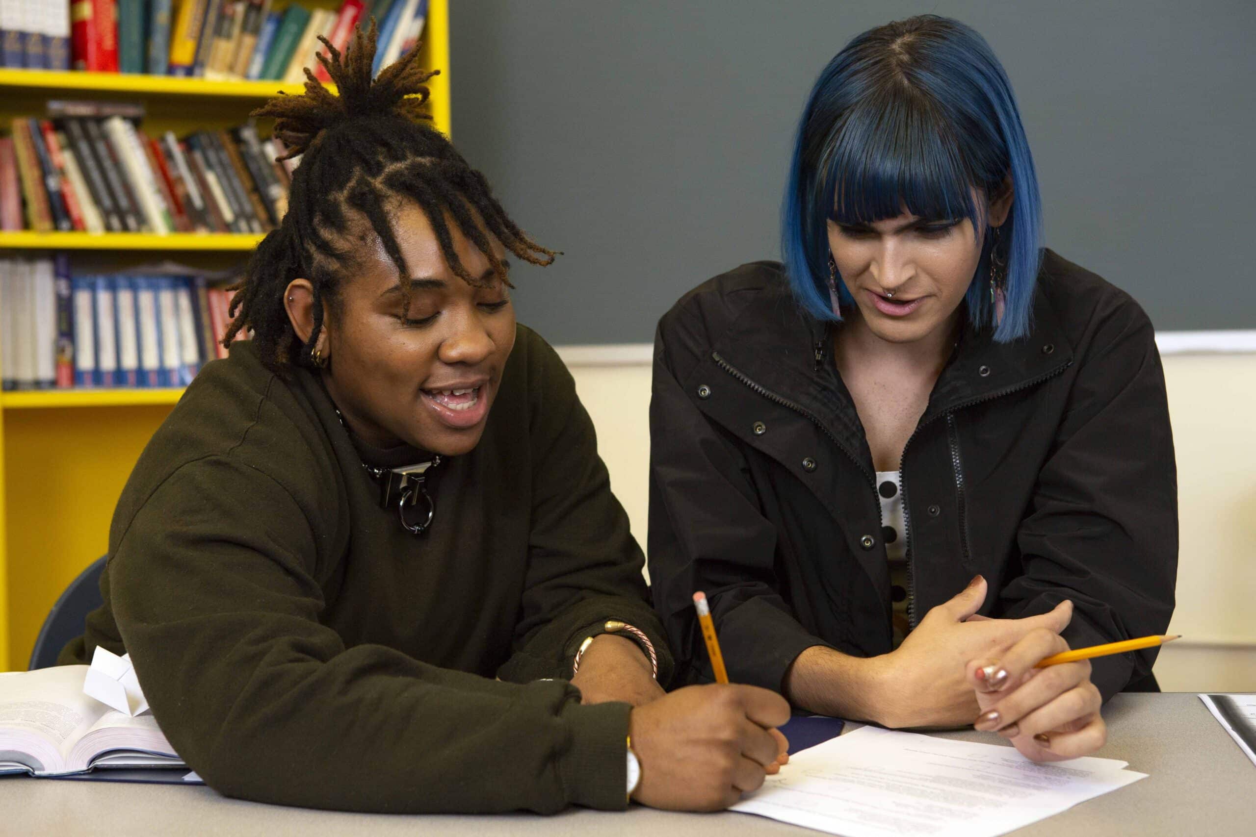 Two non-binary students doing work together in class