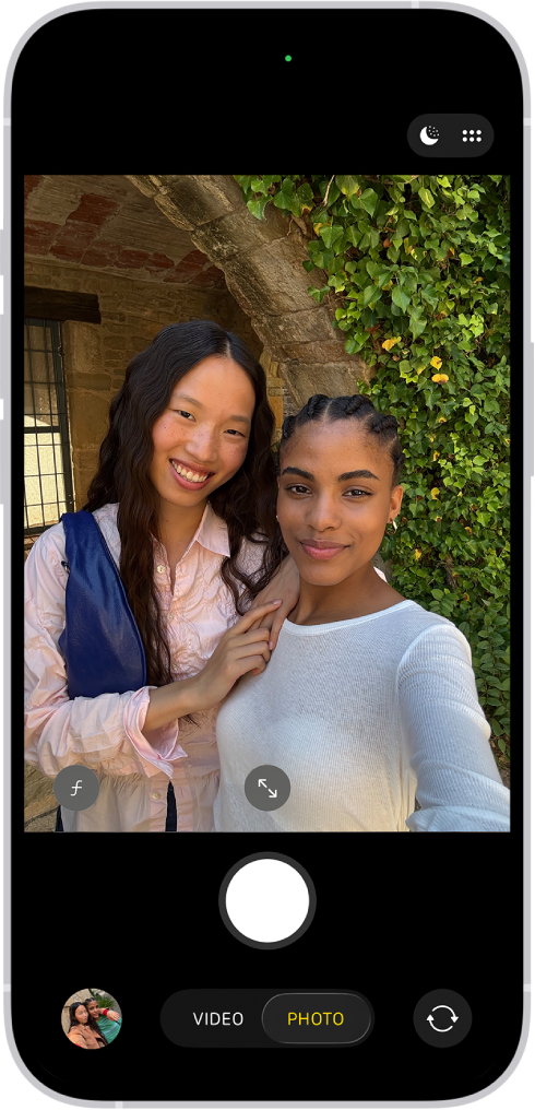 The Camera screen in Photo mode. Within the camera frame, the subjects are taking a selfie.