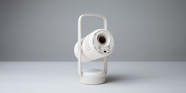 Compact white projector with a handle, designed for portable use and modern aesthetics. Compact white projector with a handle, designed for portable use and modern aesthetics.