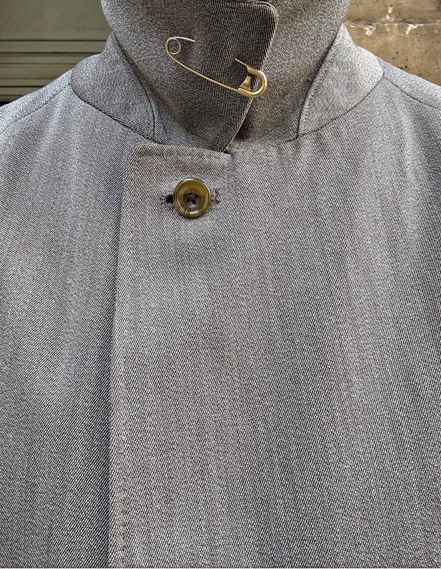 Gray coat with a safety pin and button on the collar. Gray coat with a safety pin and button on the collar.