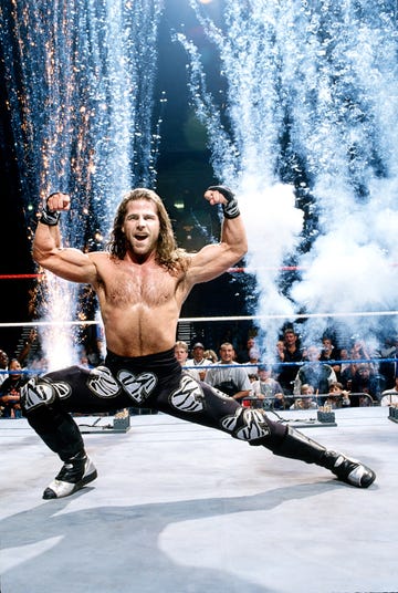 Wrestler celebrating victory with muscular pose amidst fireworks and an excited crowd in the background. Wrestler celebrating victory with muscular pose amidst fireworks and an excited crowd in the background.