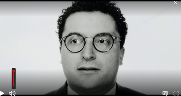 Black and white portrait of a man with curly hair and glasses, looking directly at the viewer. Black and white portrait of a man with curly hair and glasses, looking directly at the viewer.