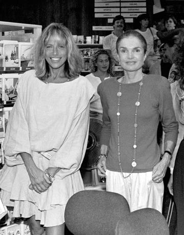 Two women smiling in a bookstore, surrounded by shelves of greeting cards and fans in the background. Two women smiling in a bookstore, surrounded by shelves of greeting cards and fans in the background.