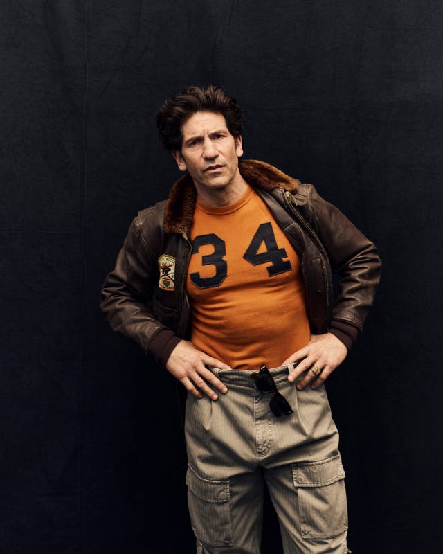 Individual wearing a brown leather jacket and orange shirt with the number 34. Individual wearing a brown leather jacket and orange shirt with the number 34.