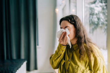 Sick woman blowing her nose with tissue paper at home, suffering from allergy or flu doctors recommend ways to get rid of phlegm