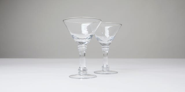 Two clear glass cocktail glasses on a plain surface against a neutral background. Two clear glass cocktail glasses on a plain surface against a neutral background.