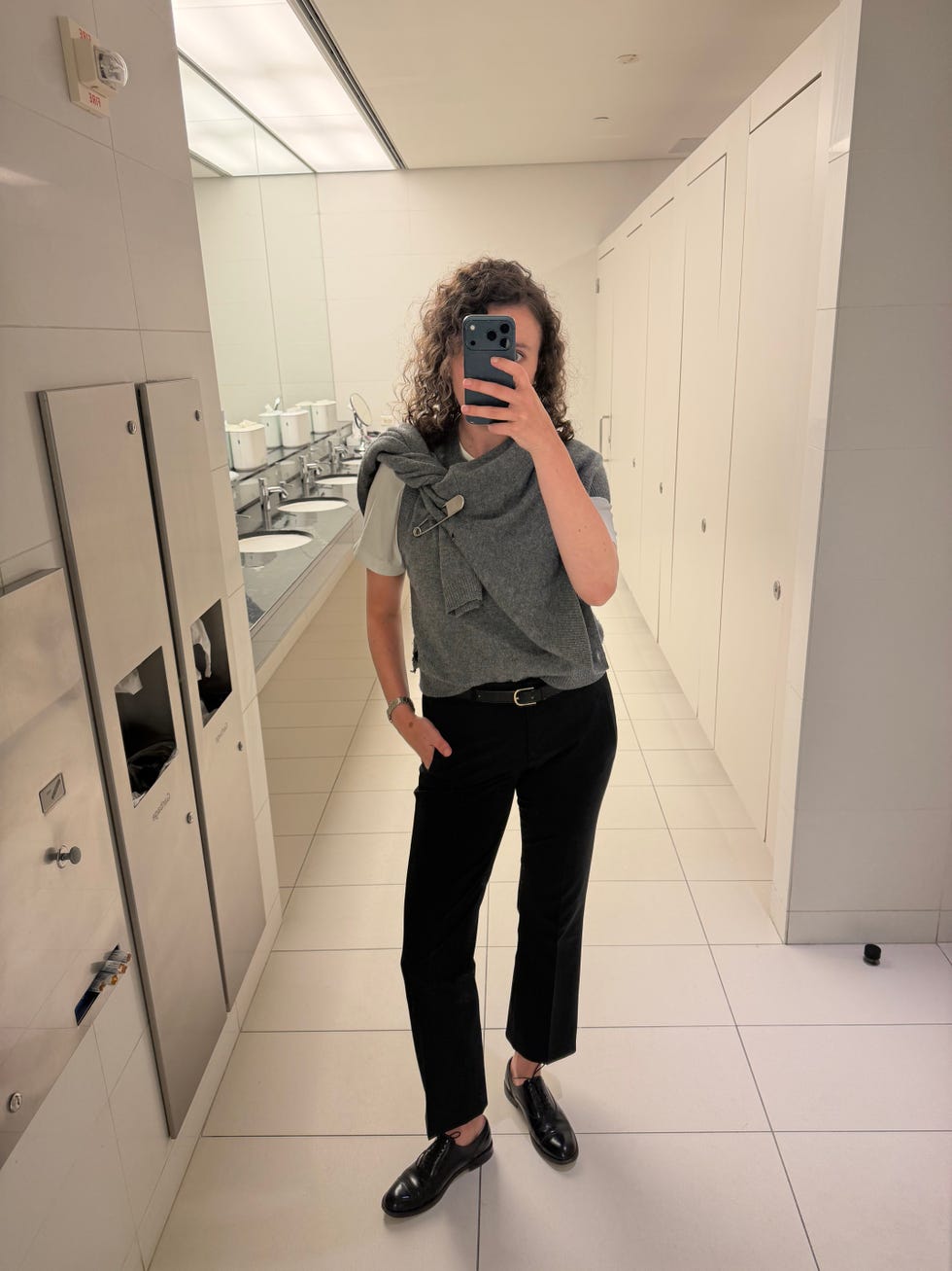 Person taking a mirror selfie in a modern restroom. Person taking a mirror selfie in a modern restroom.