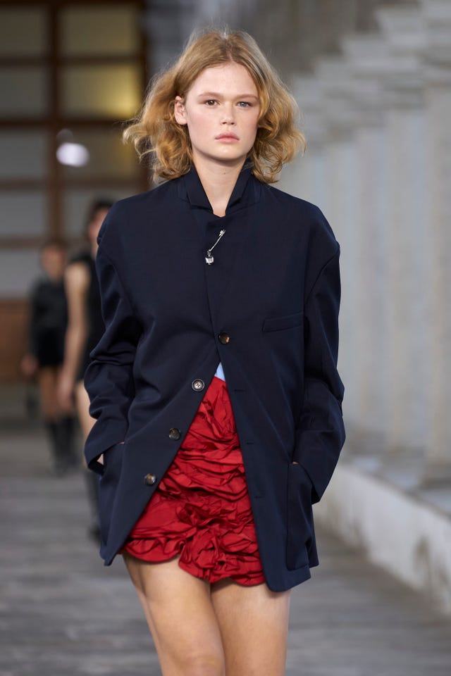 Fashion model walks runway in navy blazer and red skirt. Fashion model walks runway in navy blazer and red skirt.