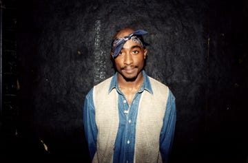 Tupac Shakur Live In Concert Tupac smiles at camera against black wall