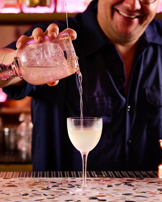 Bartender pouring a cocktail from a shaker into a chilled glass Bartender pouring a cocktail from a shaker into a chilled glass