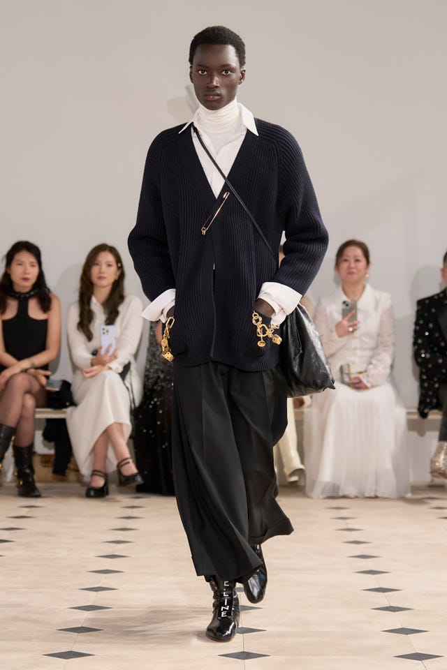Model in black and white outfit walking runway at a fashion show. Model in black and white outfit walking runway at a fashion show.
