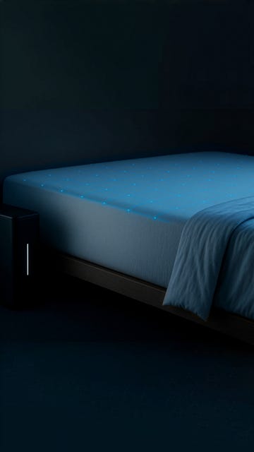 A modern bed with a glowing mattress and a sleek nightstand in a dark room. A modern bed with a glowing mattress and a sleek nightstand in a dark room.
