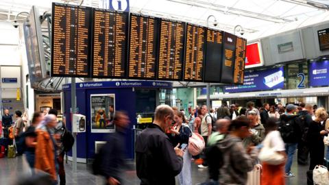 Passengers walk in front a screen showing information about cancellations inside Manchester Piccadilly train station after a major disruption to rail service in the Midlands and northwest England on August 06, 2026 in Manchester, England.