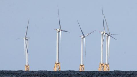 Five wind turbines mounted on yellow metal structures embedded into the sea bed at the Block Island Wind Farm off the coast of Block Island, RI.