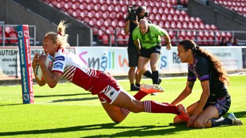 Wigan Warriors' Anna Davies (left) diving into the corner with a St Helens defender on her knees unable to stop her