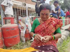ग्यासको पालो कुर्दै बसिरहेकी महिला बत्ती कात्दै