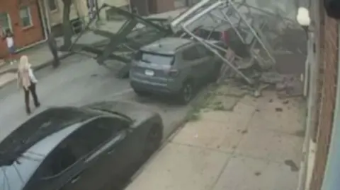 Debris from a collapsed building lies in the road and on top of a car.
