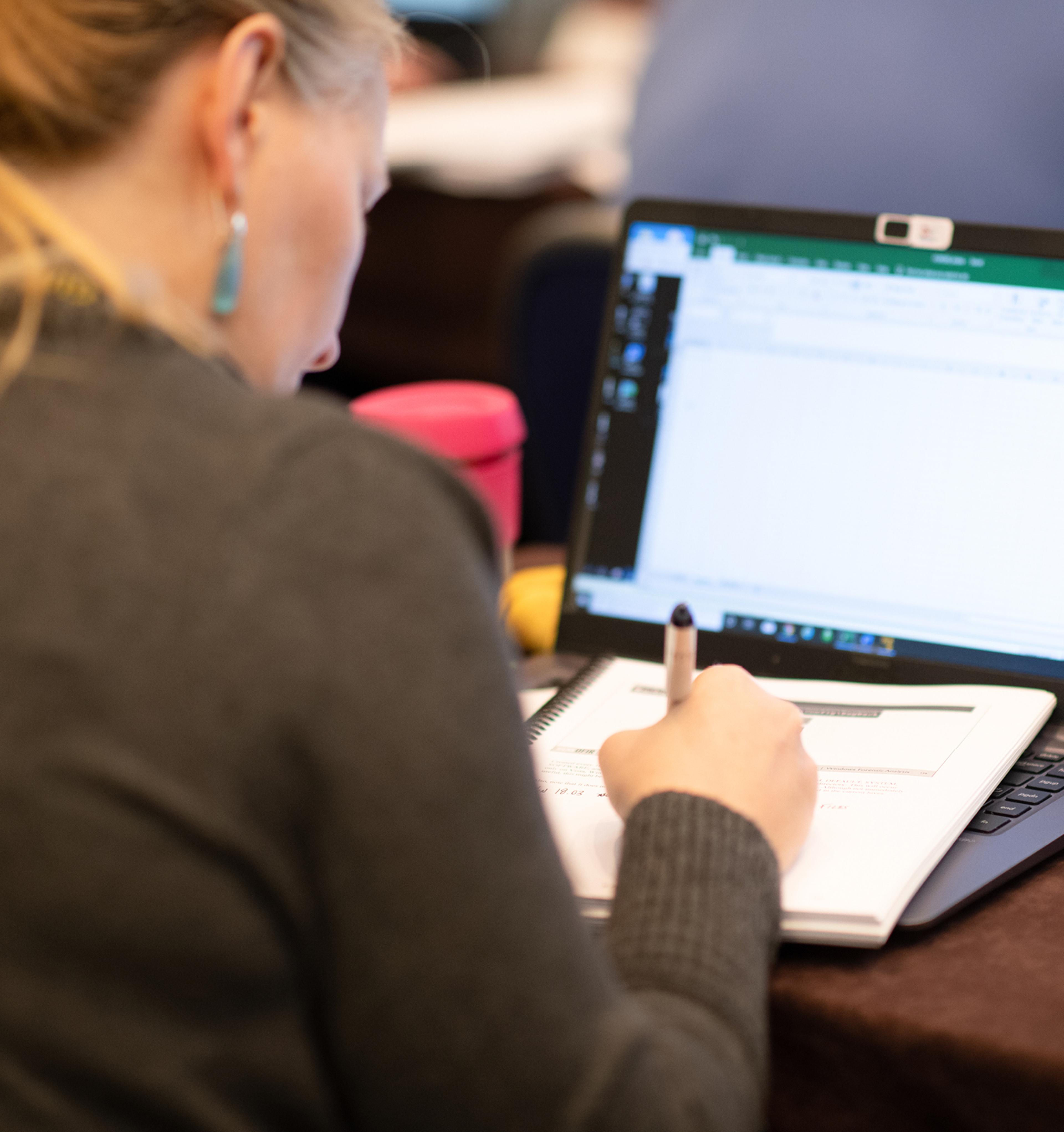 Woman Taking Notes Off a Laptop
