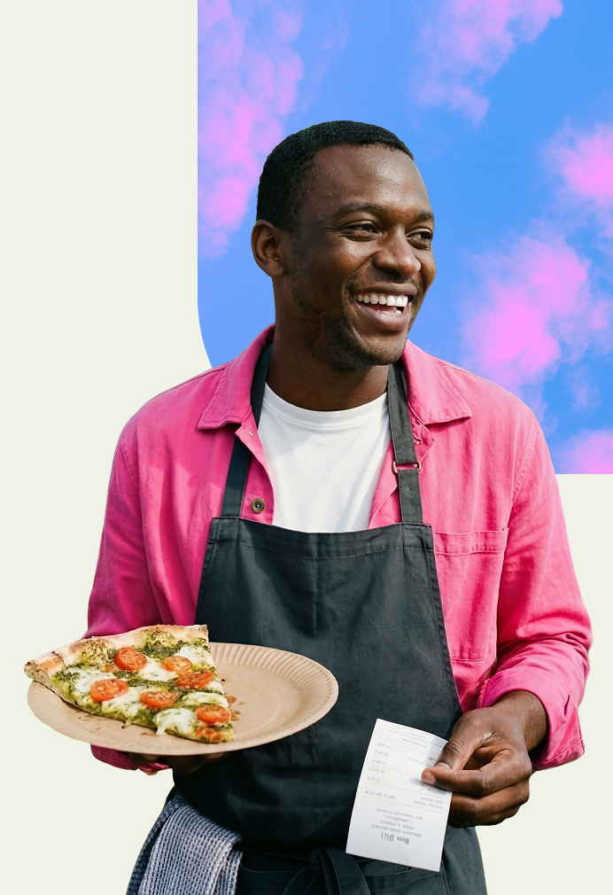 A person smiles while serving pastries on a tray at a counter in a bright, modern kitchen setting.