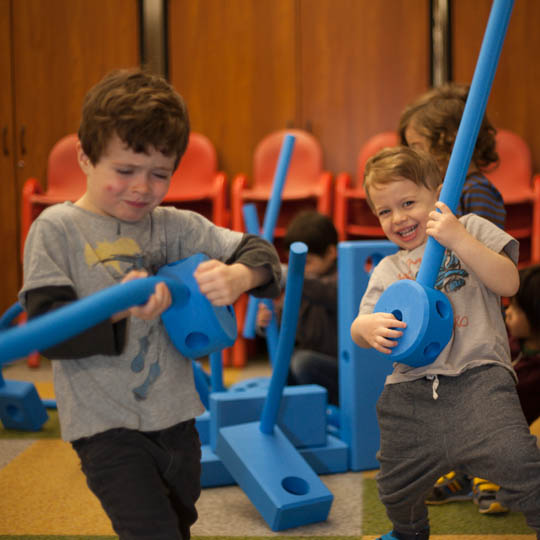 Two boys building with Medium Blue Blocks in an outdoor play area.