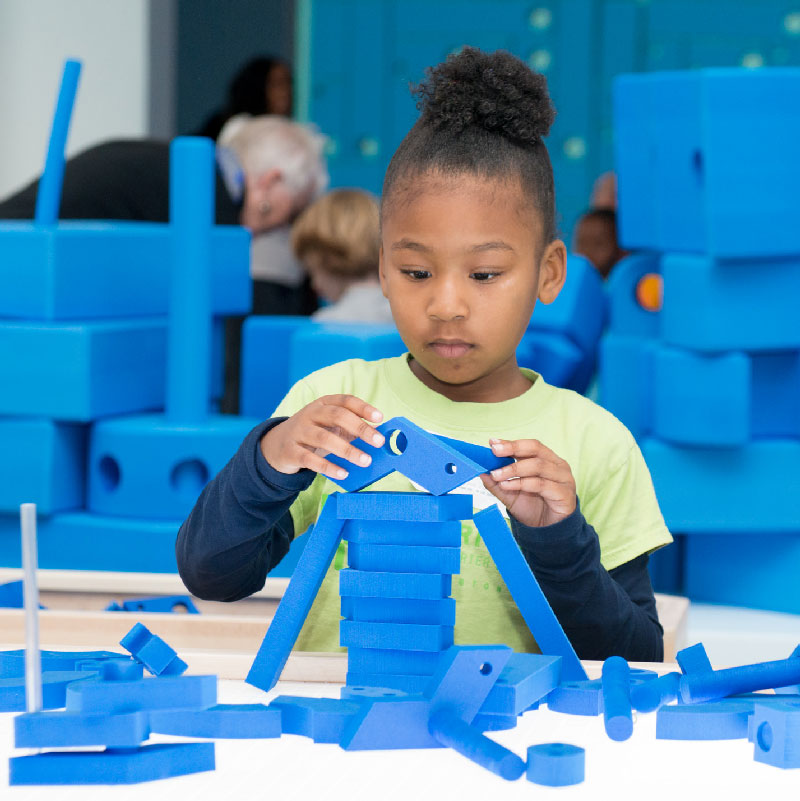A child playing with Imagination Playground Small Blue Blocks on a table.