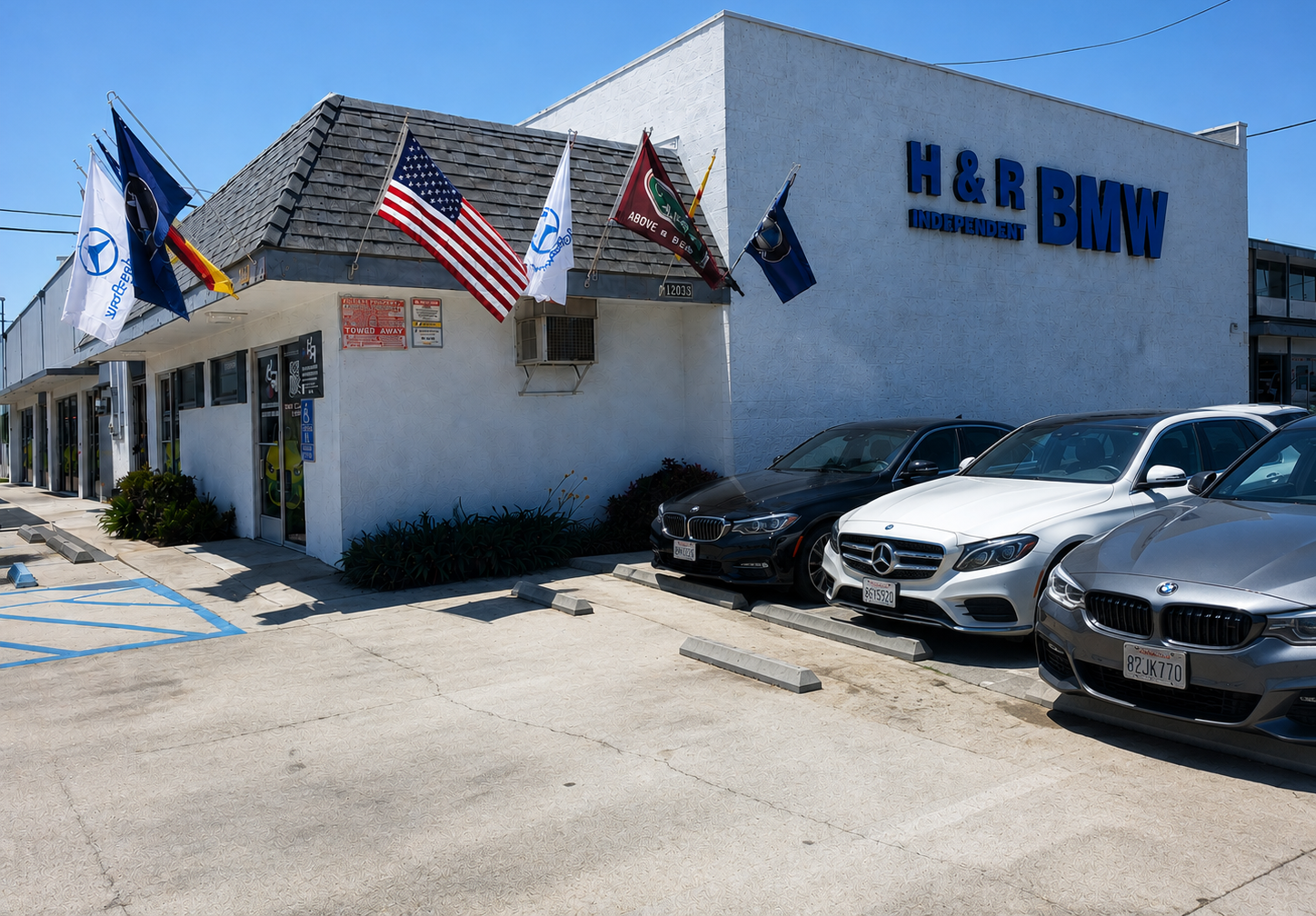 Exterior of H&R Block office with American flags and parked cars on a sunny day