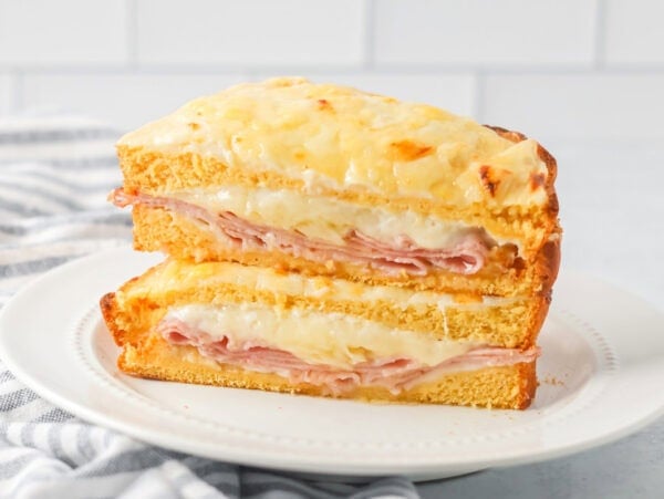 Croque Monsieur recipe cut in half and stacked on each other on white plate.