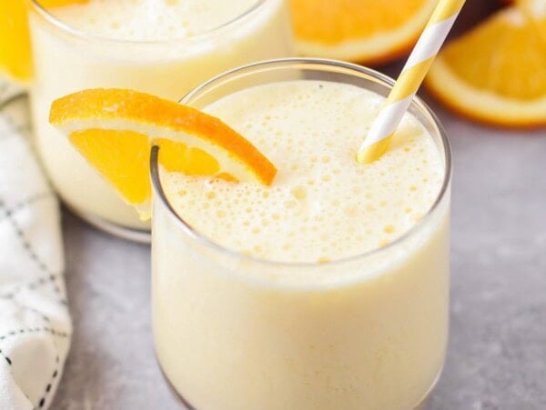 Copycat Orange Julius recipe poured into glass cup with orange wedge on top.