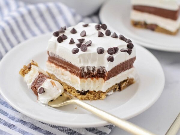 Chocolate delight slice served on a white plate with a bite missing.
