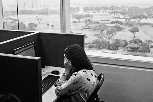Photograph of a woman at a desk with her hands to her face